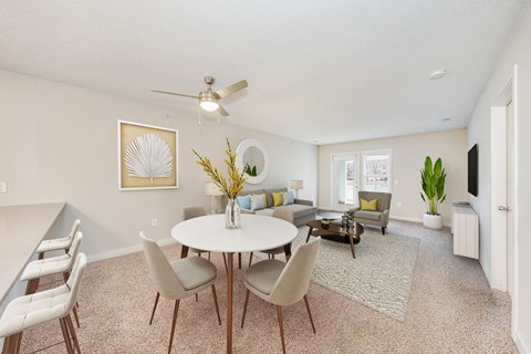 a living room with a table and chairs and a ceiling fan